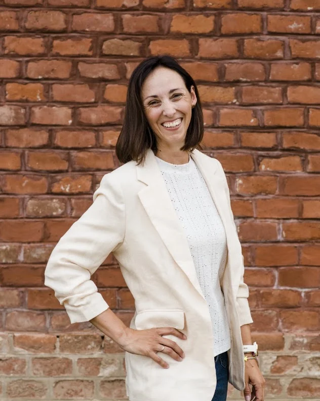 Simone Wiesinger-Springer lächelt vor einer Ziegelmauer direkt in die Kamera